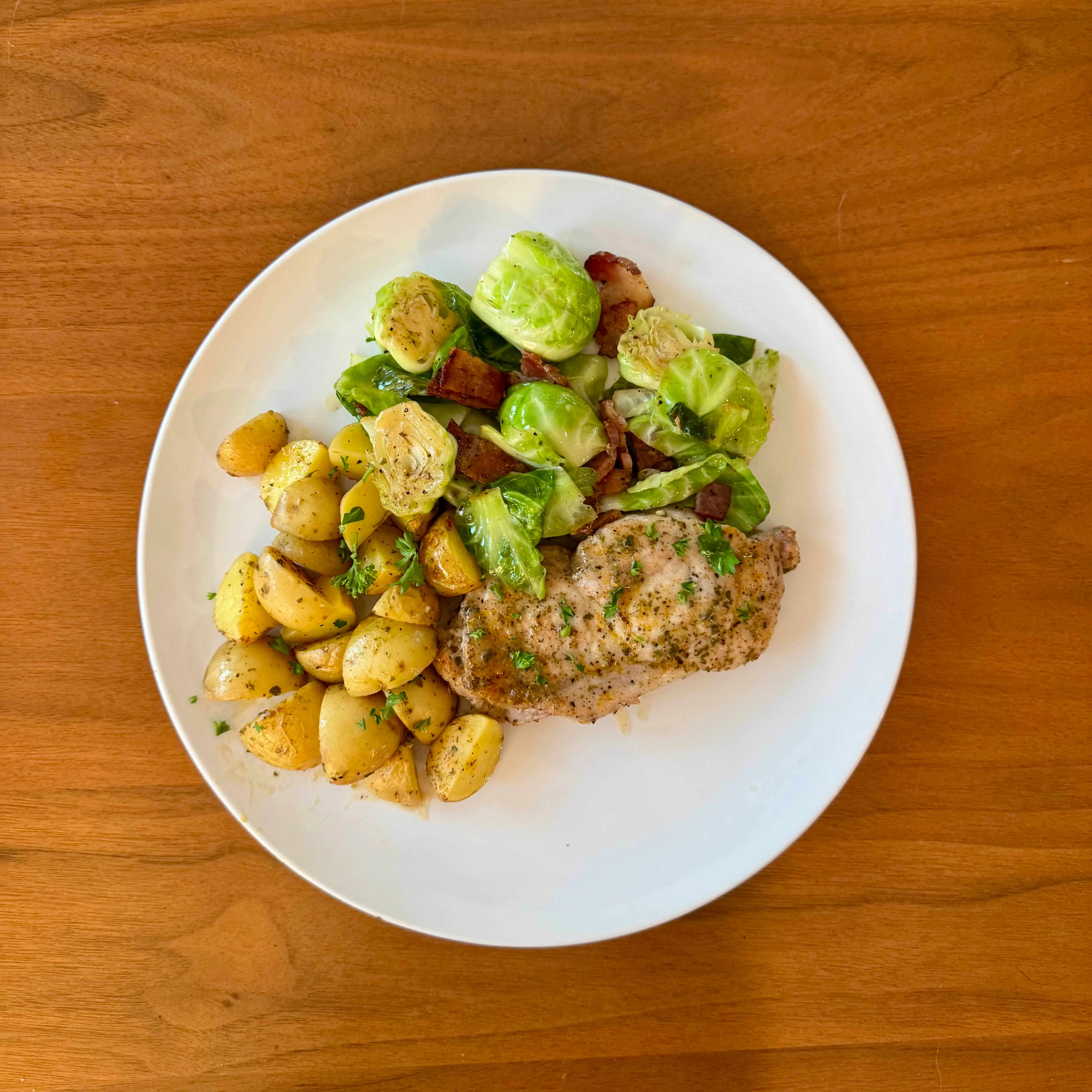 A pork chop in a creamy dijon-thyme sauce, halved brussels sprouts cooked with bacon, and golden baby potatoes tossed with parsley.
