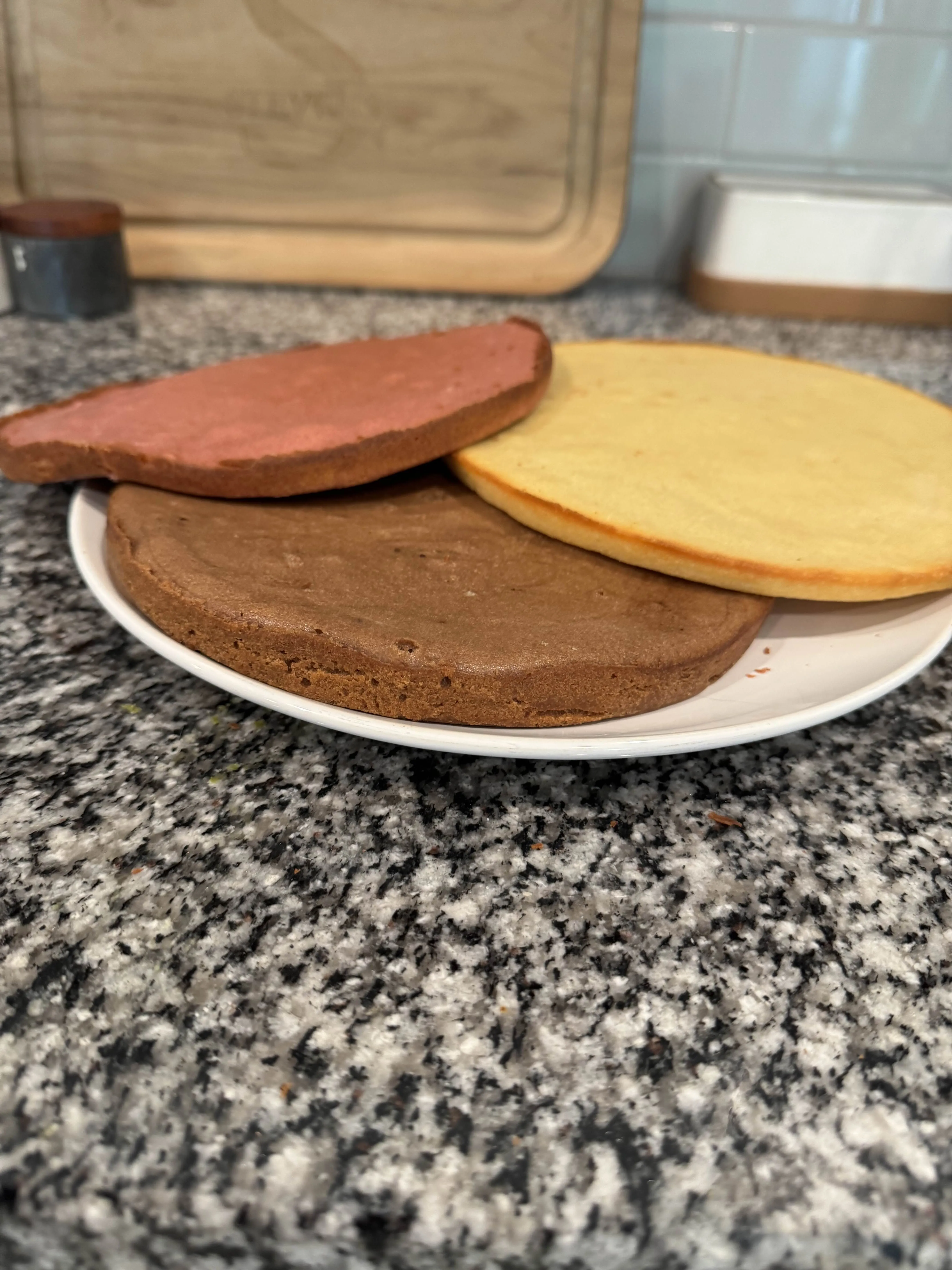 Side view of the same three cake layers showing their different browned edges and colors, still unfrosted.