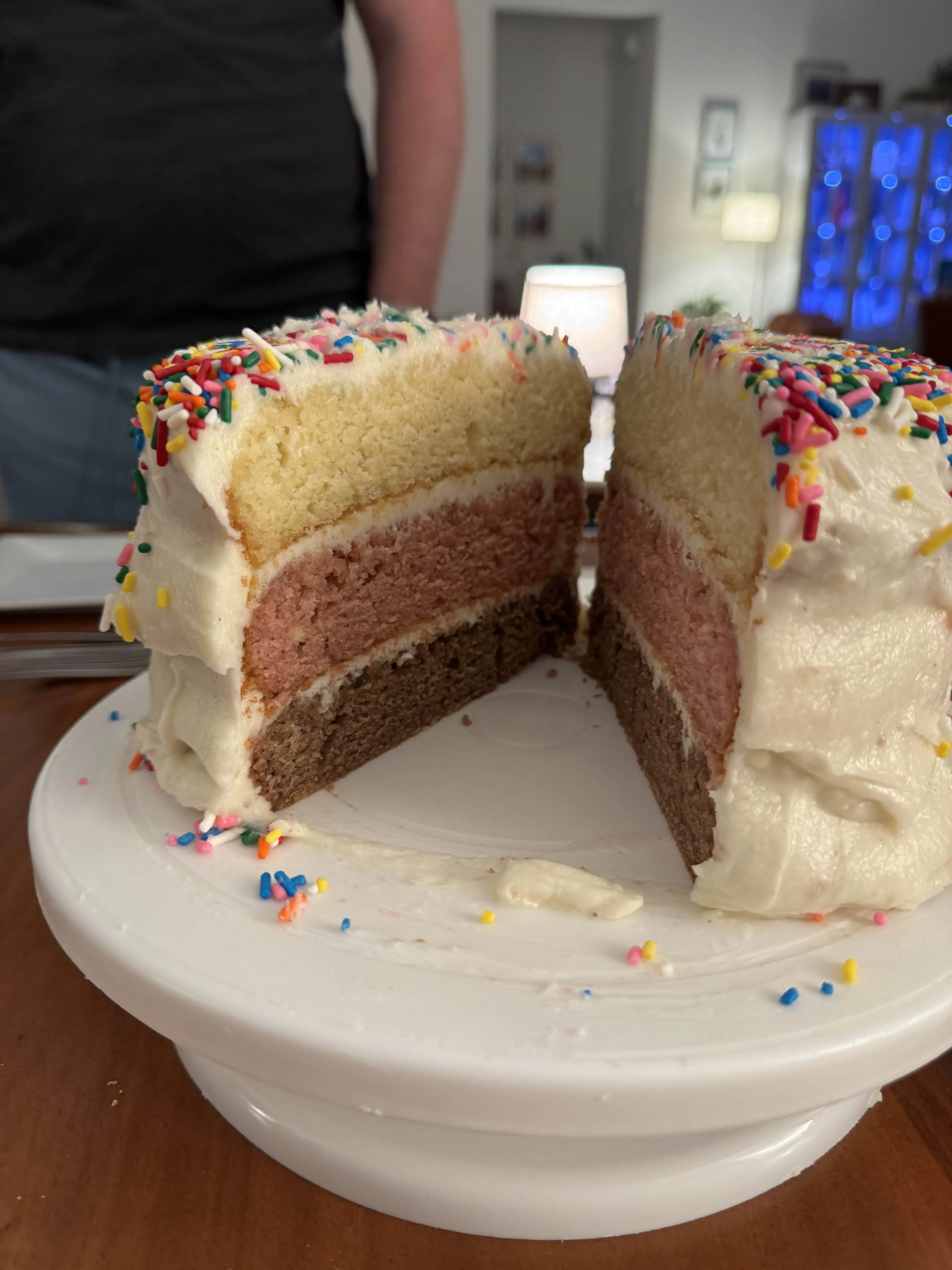 A shallow bowl of beef lo mein - long yellow noodles tangled with thin-sliced beef, caramelized onion rings, and sesame seeds - on a wood table.